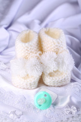 Fototapeta na wymiar White baby boots on cloth close-up