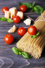 Raw pasta with tomatoes and cheese on wooden background