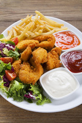 Nuggets and chips on a plate served with dip and salads