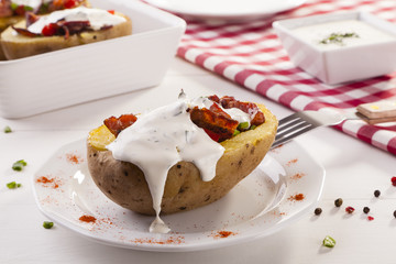 Baked potatoes stuffed with bacon served with dill sauce