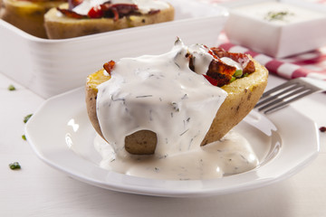 Baked potatoes stuffed with bacon served with dill sauce