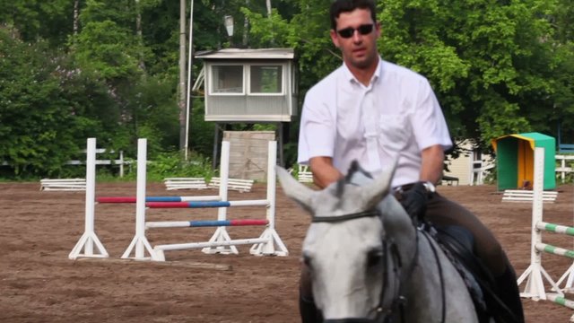 Horseman rides on horseback equestrian field with bars and other equipment