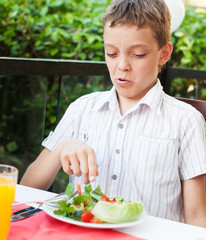 Child with disgust looking at vegetable salad