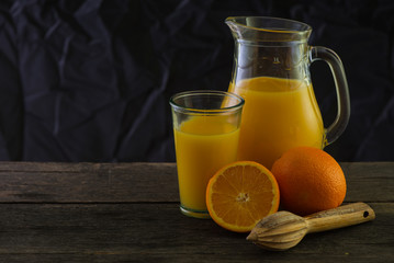 Jug with fresh orange juice, still life art on dark background
