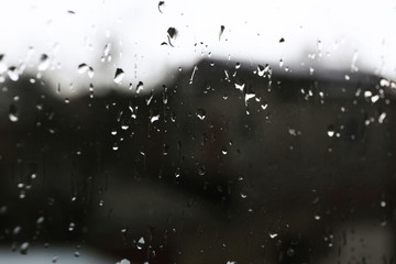Raindrops on glass window overlooking the street on background