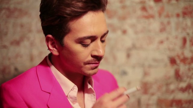 Young man in pink suit took a break with cigarette 