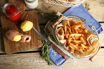 Tasty french fries in metal basket on wooden table background