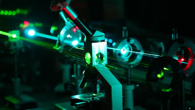 microscope and multi-colored lasers passing in it in dark close up