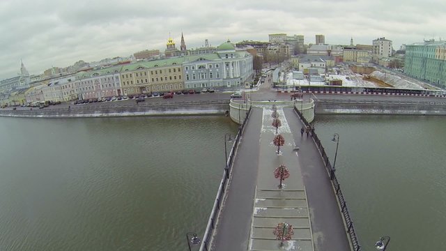 Cityscape with cars ride by quay near pedestrian bridge