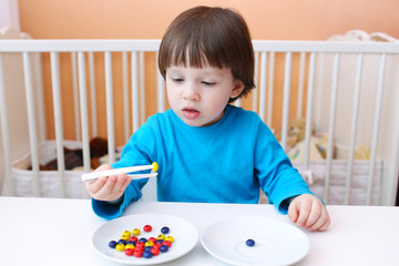 2 years boy plays with pincers and beads at home