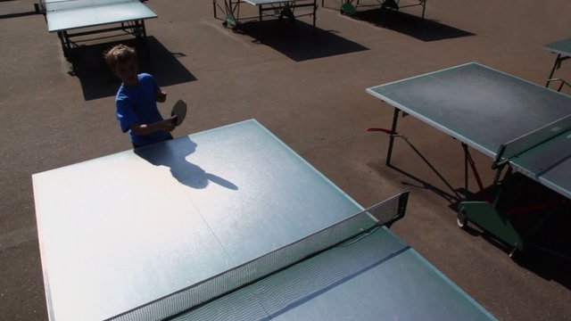 Boy in blue shirt plays tabletennis, view from above