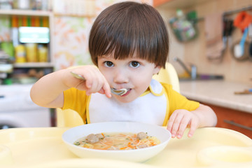 2 years boy eating soup with meat balls at home kitchen © ivolodina