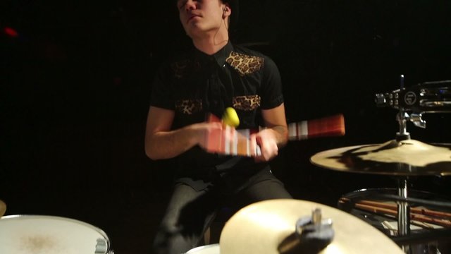 Young drummer in hat plays in night club with smoke