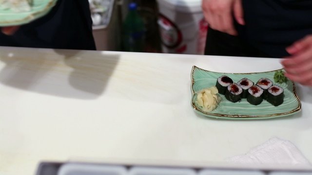 Two men prepares pair of plates with different rolls on table