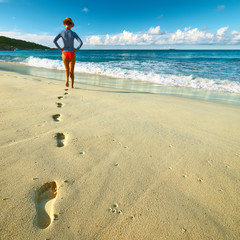 Woman at beautiful beach. Focus on footprints.