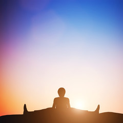 Woman in wide angle bend yoga pose meditating at sunset. Zen