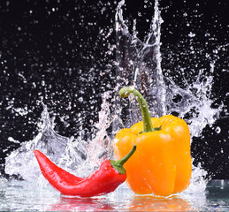 drops of water fall on the red and yellow pepper, splash