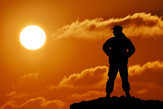 Silhouette of military soldier officer with weapon at sunset