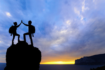 Silhouette of two people man girl success on mountain.