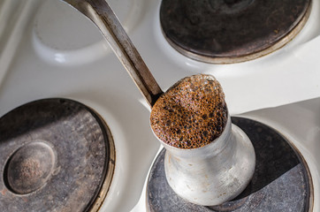 Turkish coffee pot with boiling coffee on an old electric stove