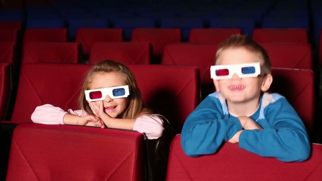 Little girl and boy in 3D glasses in the cinema watching a movie