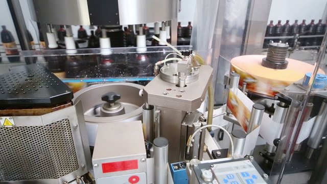 Many brown bottles moving on labeling line on large brewery