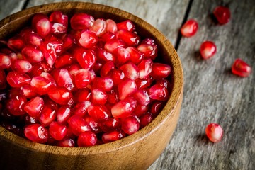 ruby pomegranate grains closeup in a wooden bowl on a table