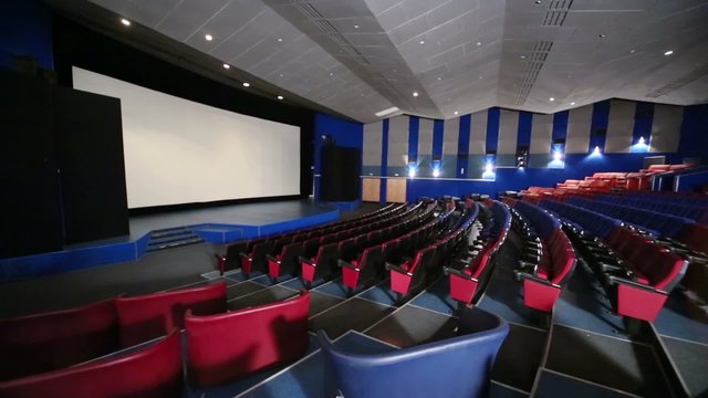 Rows of seats with screen in dark hall cinema theater