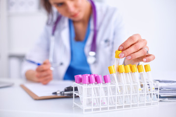 Woman researcher is surrounded by medical vials and flasks