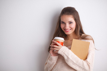 Portrait  a young woman with cup of tea or coffee, holding book