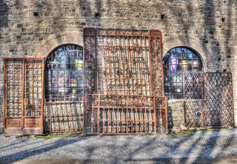 metal gates leaning on a stone wall in hdr