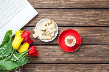 Cup of cappuccino with heart shape and computer