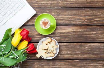 Cup of cappuccino with heart shape and computer