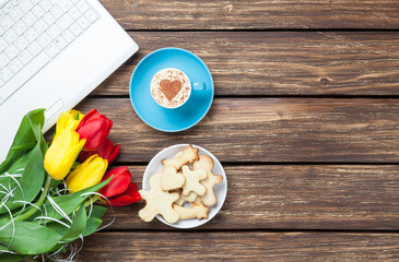 Cup of cappuccino with heart shape and computer