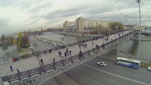 Tourists walk by Patriarshy bridge against cityscape