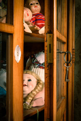 Slightly opened glass cabinet with antique dolls