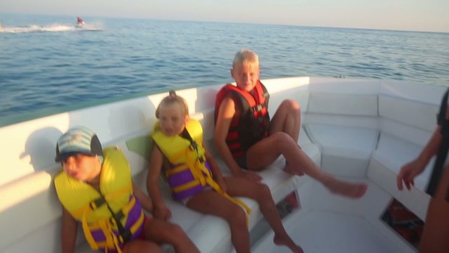 children and mother have fun on motor boat with soft couch