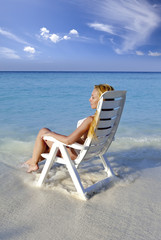 Young pretty woman in a beach chair in sea