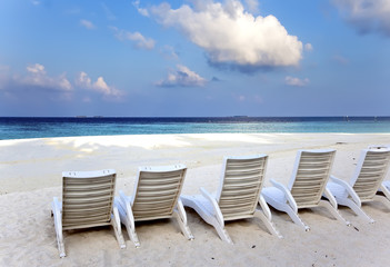 A number of empty beach chairs before the sea at sunrise