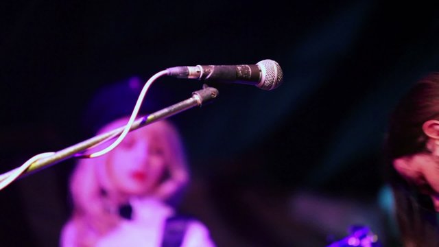 Young man sings and plays on guitars with woman on stage