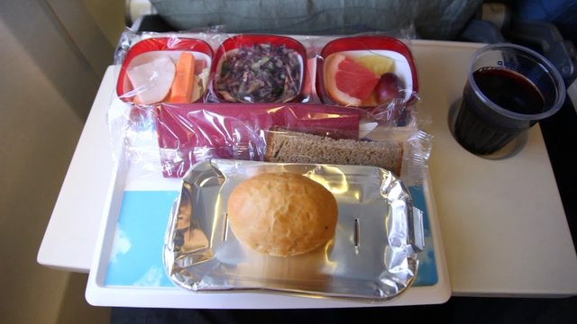 Tray of food: salad, fruit, bread, drink on the plane. 