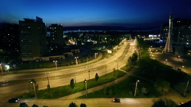 Night cityscape with traffic near monument of rocket