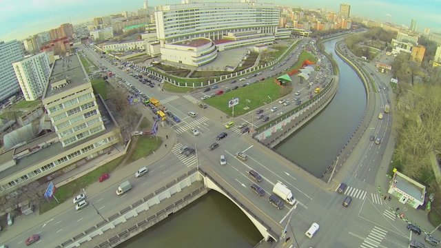 Cityscape with traffic on quay and bridge near edifice of MGTU