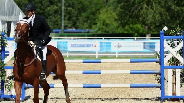 Horseman on horse jumps over barrier at competitions