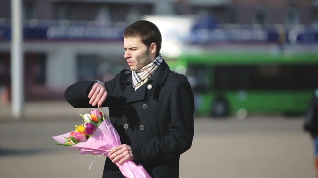 A man with flowers waiting for his woman in the city
