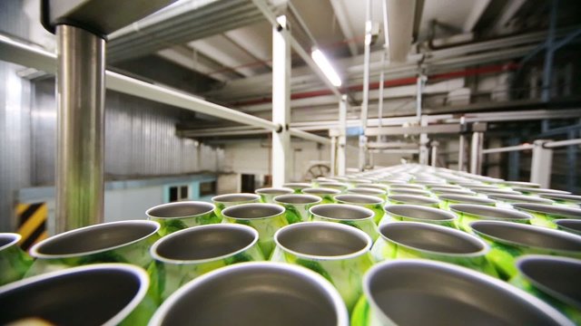 Rotating metallic cans in rows n moving line in workshop