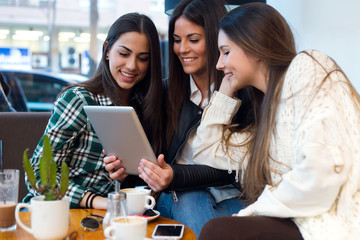 Three young woman using digital tablet at cafe shop.