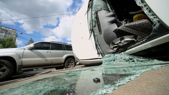 Broken glass near two damaged cars at place of road accident