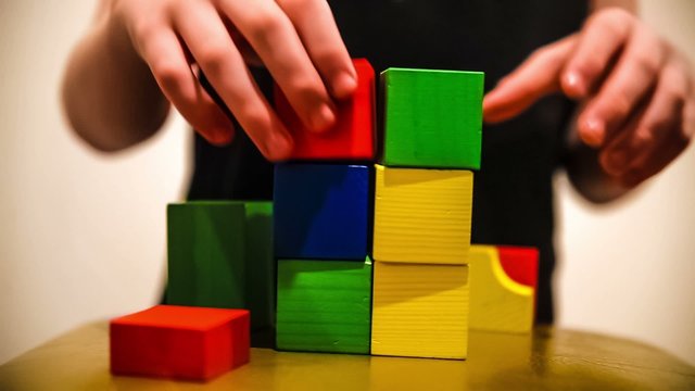 teenager boy builds tower  of bricks blocks play a major hand
