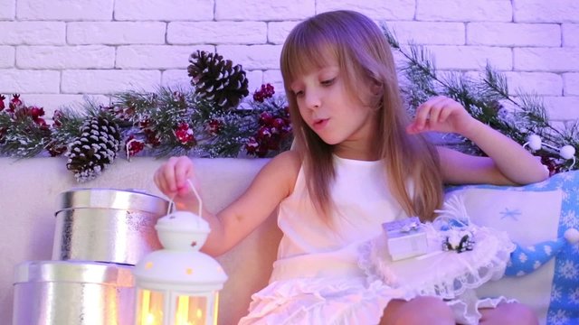 girl sitting on sofa with Christmas gifts and holding lantern